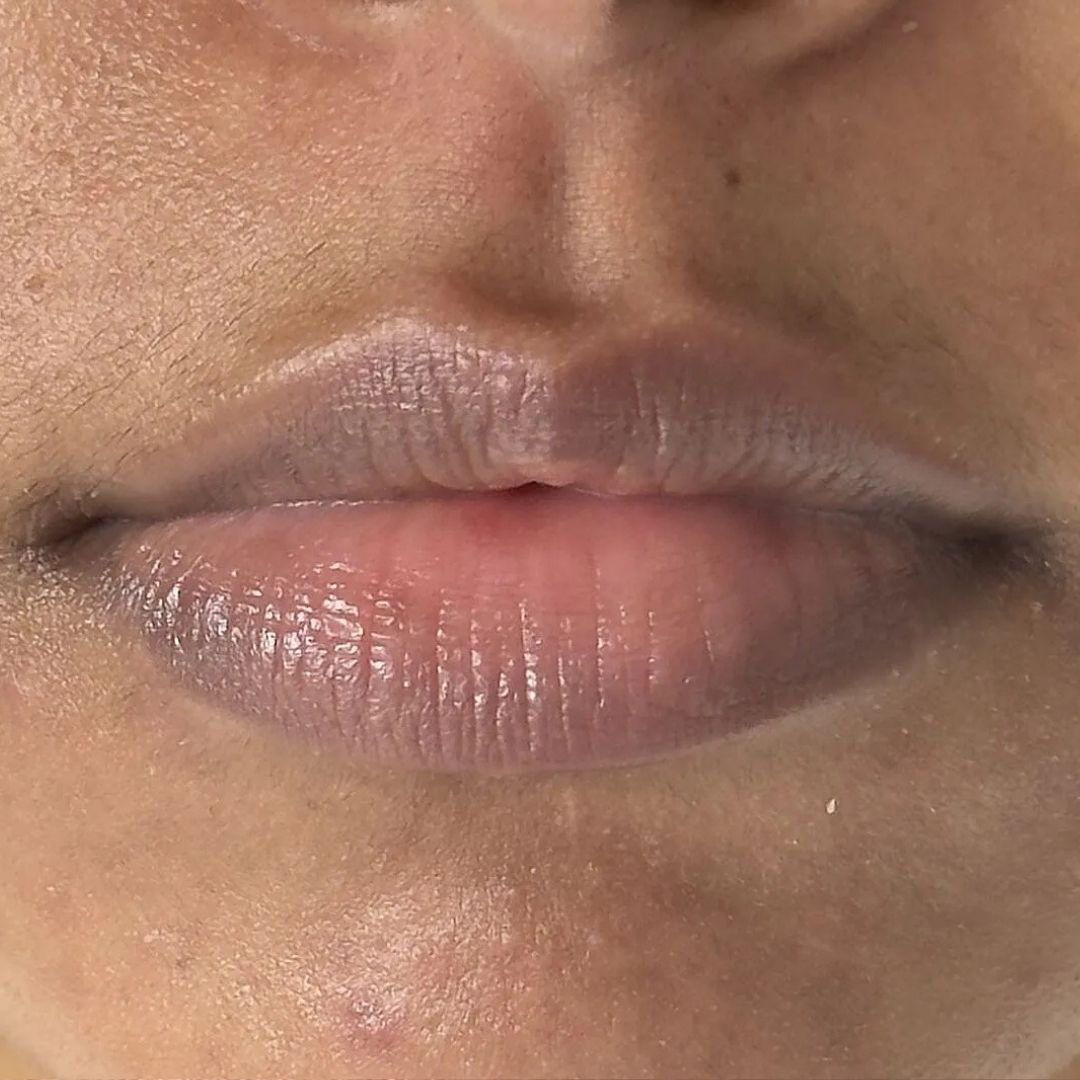 Close-up of a person's lips showing a glossy, muted mauve-pink lip color.