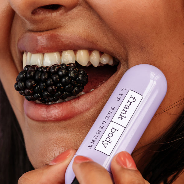 Person holding a blackberry and a lip balm labeled 'Frank Body' with a blurred background