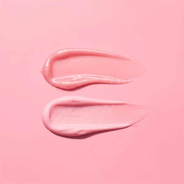 Two swatches of glossy light pink cream or gel makeup applied horizontally on a solid pink background.
