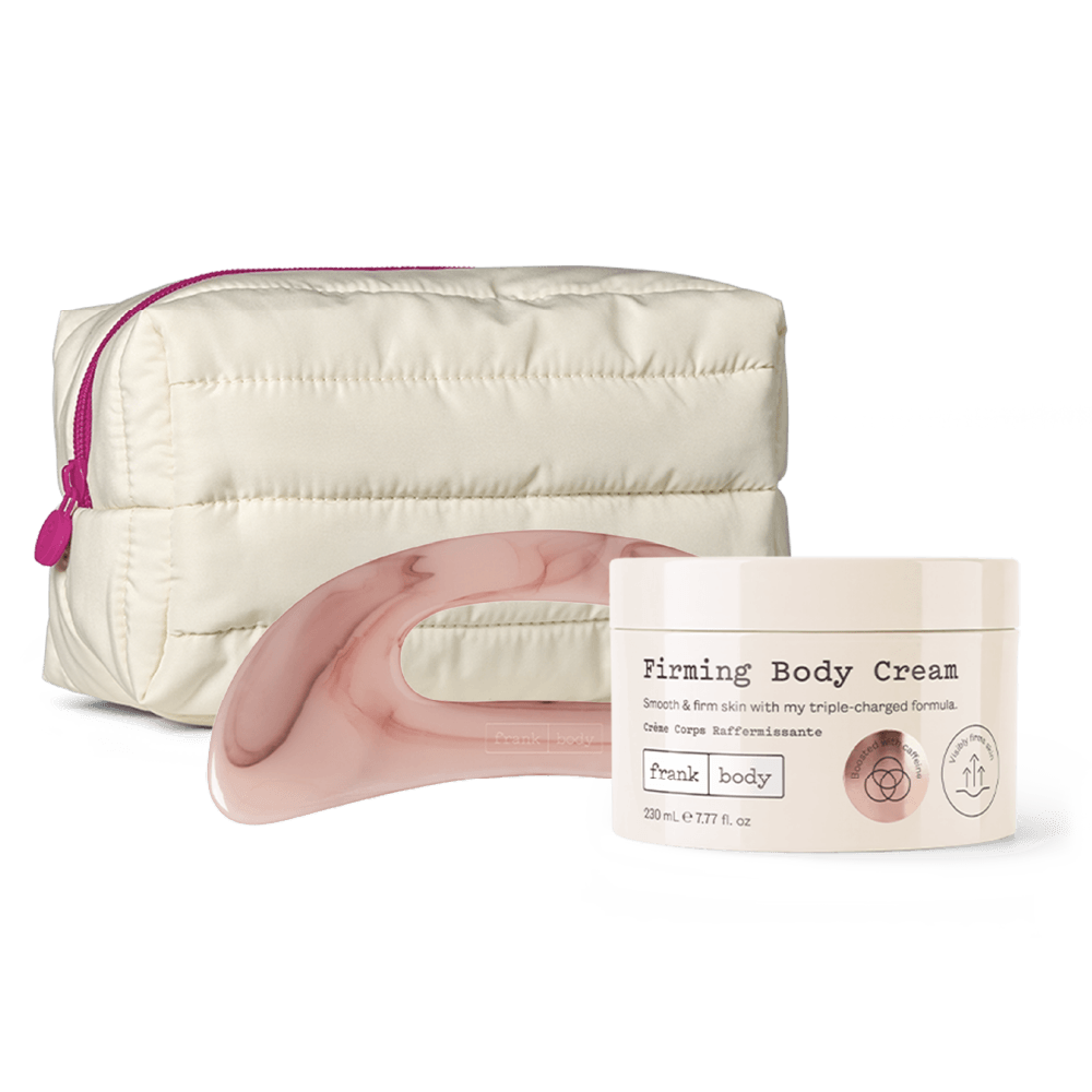 A skincare set featuring a cream-colored quilted puffer pouch with a pink zipper, a translucent pink curved silicone tool, and a cream-colored jar of 'Firming Body Cream' by 'frank body' on a white background.