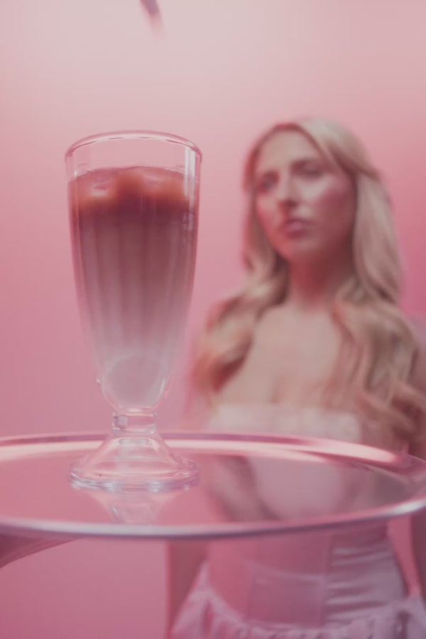 frank body You'll Be Whipped gift set video: a model unboxes the kit and scoops Coconut Coffee and Espress-o whipped body scrubs against a pink backdrop.