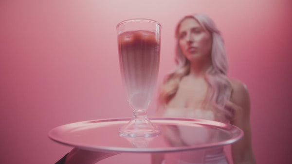 frank body You'll Be Whipped gift set video: a model unboxes the kit and scoops Coconut Coffee and Espress-o whipped body scrubs against a pink backdrop.