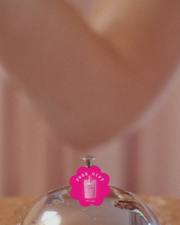 frank body holiday campaign video: a gloved hand rings a service bell, then a model in a pink dress sips from a glass beside a buffet of cakes and gift sets, with a free gift badge.
